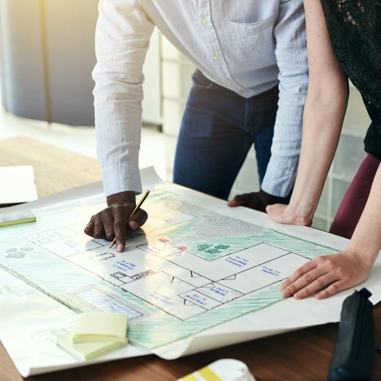 Planbesprechung im Büro Zwei Planer betrachten und markieren einen Plan auf einem Planungstisch